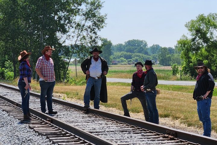 a group of people standing on a train track with trees in the background