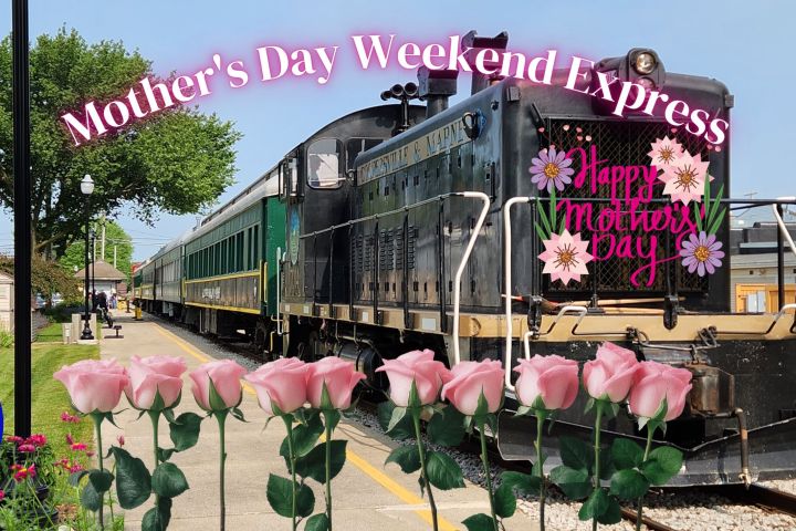 Train at station with 'Mother's Day Weekend Express' banner and pink roses in foreground.