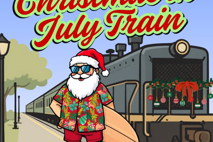 Santa in summer attire by a train, decorated for Christmas in July.