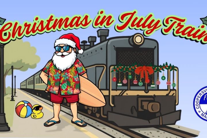 Santa in summer attire with surfboard near a decorated train, text reads 'Christmas in July Train.'